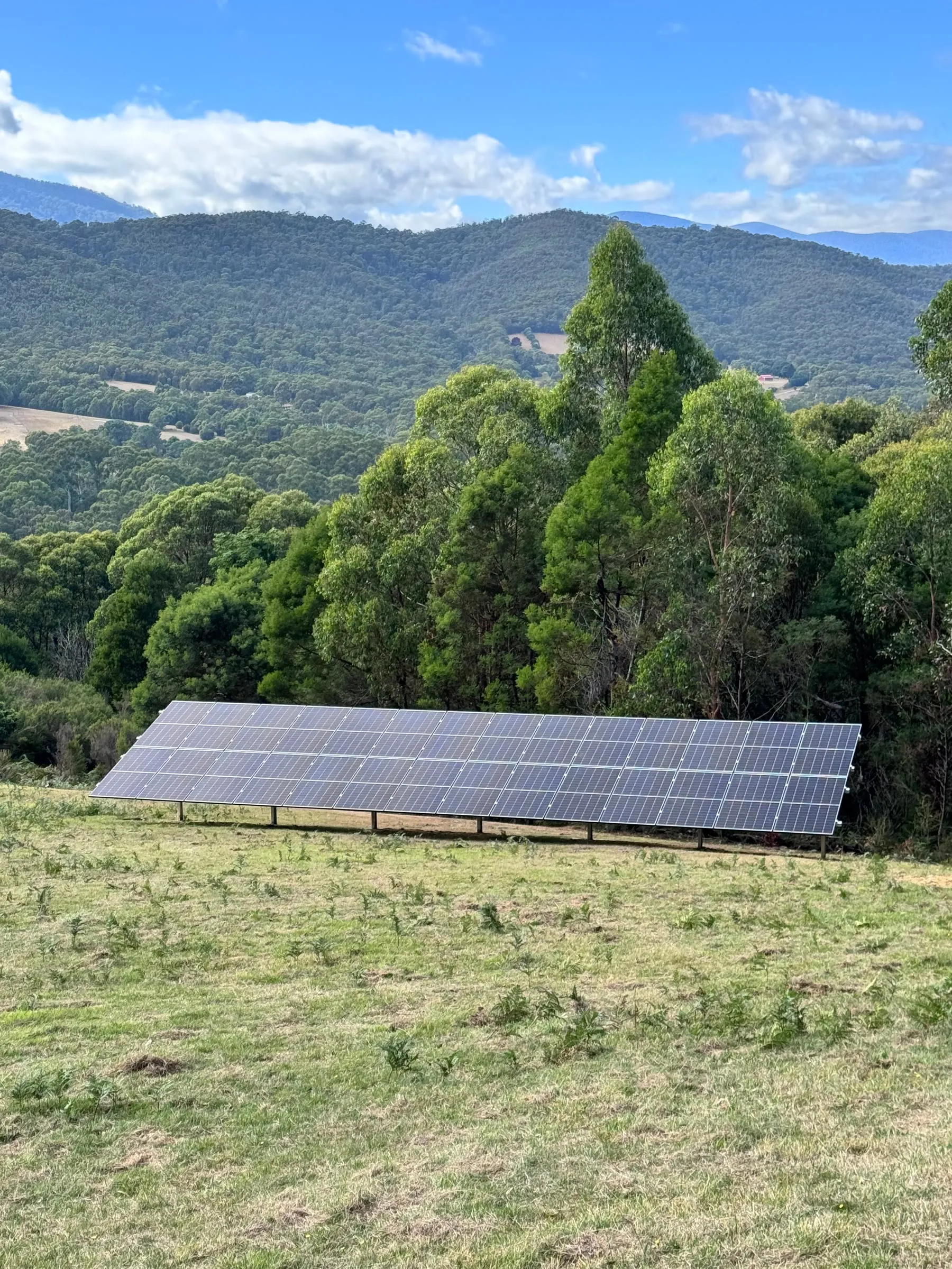 A long ground-mounted solar array in a hillside paddock